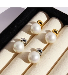 Detailed view of pearl stud earrings with gold and silver pebble-shaped metal bases