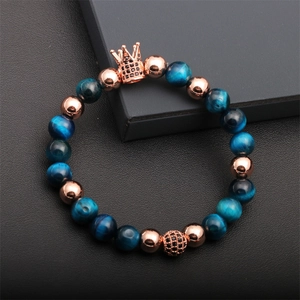 Detail of luxury beaded bracelet featuring blue tiger eye stones and rose gold crown charm