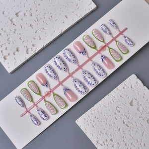 Detail of press-on nails featuring blue floral patterns and 3D flower nail art designs