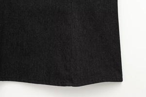 Dettaglio delle cuciture di qualità e della trama twill denim nero sull'orlo del capo
