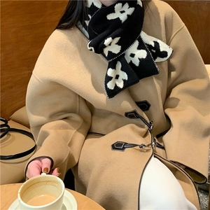 Detail of flower knit scarf paired with camel wool coat featuring horn buttons and trim