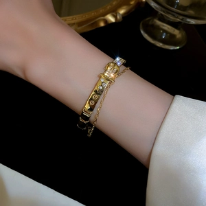 Detail of gold-plated bangle featuring buckle design with zircons and screw motifs