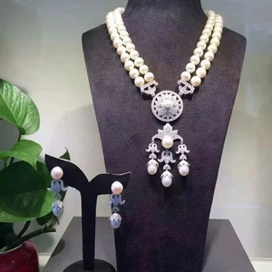 Detail of luxury double-layer pearl necklace and earrings with silver floral pendant