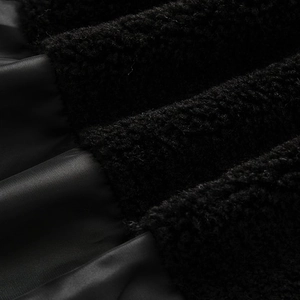 Detail of black smooth fabric stitched with soft faux shearling fleece texture