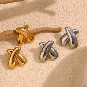 Detailed view of geometric X-shaped earrings in polished gold and silver finishes