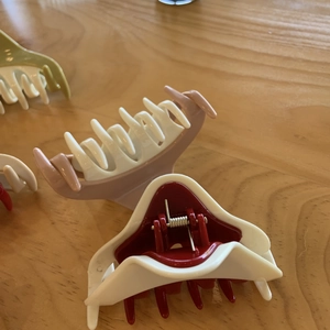 Detailed close-up of three colorful minimalist triangle hair claws on a wooden table