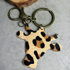 Western leopard print fur keychain with bronze metal ring on a grey concrete surface
