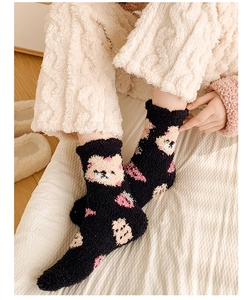 Close-up of coral fleece warm socks with cute black bear and strawberry patterns