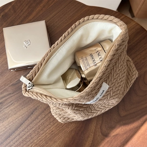 Close-up of coffee brown knit cosmetic bag showing thick cable weave and silver zipper