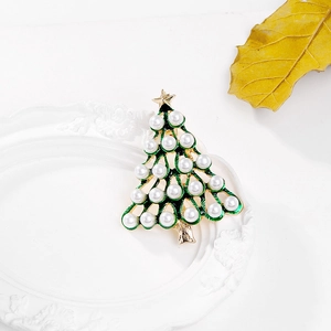 Detailed view of Christmas tree brooch with green enamel and white pearls on white plate