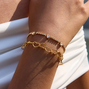 Close-up of double layered gold heart bracelets with zircons on woman's wrist