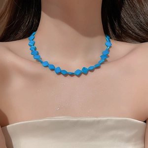Close-up of blue diamond-shaped beaded necklace on model highlighting shell-like luster