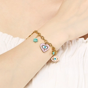 Detail eines goldenen Gliederkettenarmbands mit rosa Emaille-Anhängern und Türkisstein