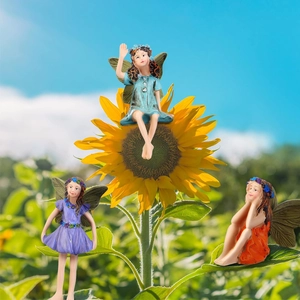 Three resin flower fairy figurines in blue, purple and orange on a sunflower