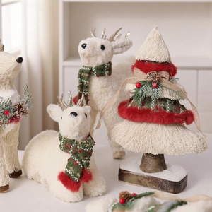 Dettaglio di renne di peluche con sciarpe e un albero di Natale bianco decorativo morbido