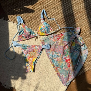 Detailed view of bohemian paisley bikini set featuring a gold pendant and matching sarong