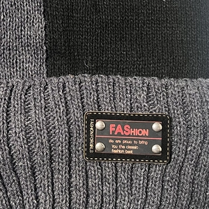 Knit beanie hat with black and grey patchwork and leather fashion label detail