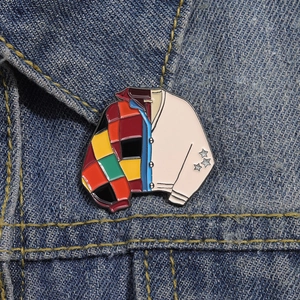 Detail of colorful cardigan enamel pin with star patterns on blue denim jacket