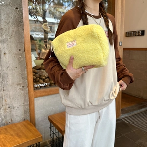 Detail of yellow fuzzy lamb wool storage bag with zipper and white motivational woven label
