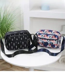 Detail of dual zipper compartments and front pocket on printed crossbody bags