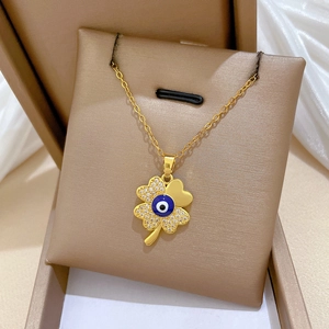 Macro view of gold clover necklace with evil eye center and pavé crystals in a jewelry box