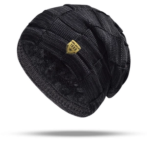 Close-up of black knitted beanie showing thick plush fleece lining and golden shield emblem