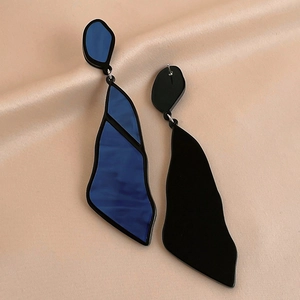 Macro detail of asymmetric geometric acrylic earrings with blue marble texture on silk