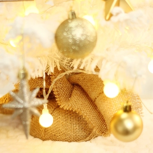 Mini flocked Christmas tree with gold baubles and LED lights wrapped in burlap base