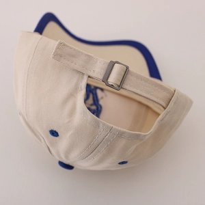 Minimalist beige cotton baby baseball cap with blue accents and metal buckle strap