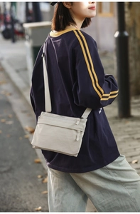 Detail of beige nylon crossbody bag with adjustable strap worn by model in street shot