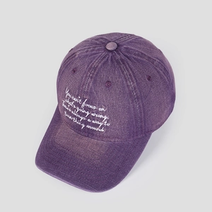 Détail de la casquette en coton lavé violet avec broderie blanche et effet vintage usé
