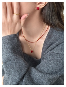 Close-up of elegant gold necklaces and heart-shaped red zircon earrings worn by model