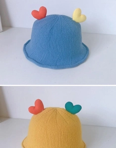 Detailed knit texture of baby fisherman hats with contrast heart decor and soft blue yellow yarn