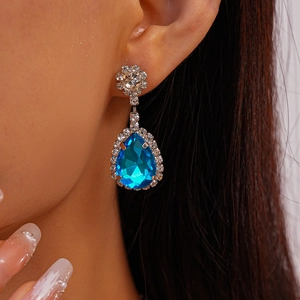 Gros plan de boucles d'oreilles goutte en argent avec pierres bleues et halo de diamants