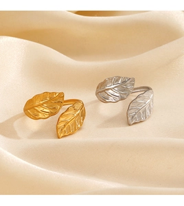 Macro shot of minimalist leaf open rings in gold and silver finish on silk fabric