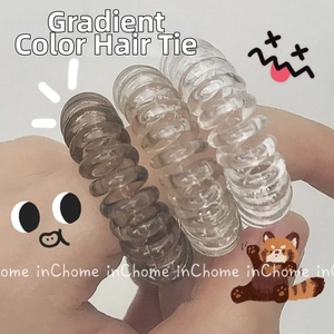 Three gradient spiral hair ties in coffee, champagne, and clear colors held by hand