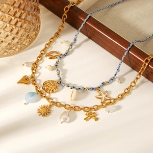 Detail of layered gold charm necklace with shells, hearts and blue woven cord jewelry