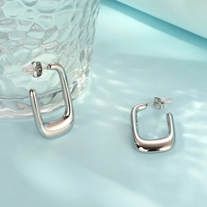 Polished silver U-shaped stainless steel earrings on a light blue water ripple background