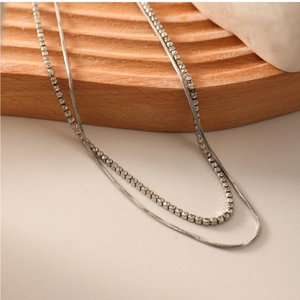 Détail d'un collier argenté à deux couches avec chaîne serpent et zircons brillants