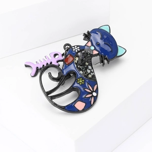 Cartoon enamel cat brooch with blue floral pattern and purple fishbone charm on white stand