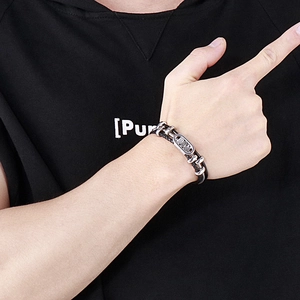 Detail of multi-layer braided black leather bracelet with silver metal charms on wrist