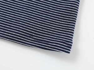 Gros plan détaillé du tissu en maille rayé bleu marine et blanc montrant l'ourlet soigné