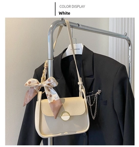Detail of cream shoulder bag with a metal buckle and a cherry print silk scarf on the strap