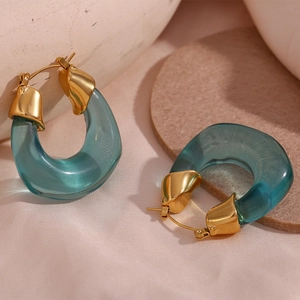 Detail of U-shaped gold hoop earring with translucent blue resin on stone