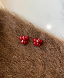 Detailed macro of red berry resin earrings with gold plating and sparkling zircon accents