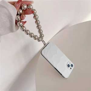 Detail of white geometric phone case held by a hand with silver metallic beaded wrist strap
