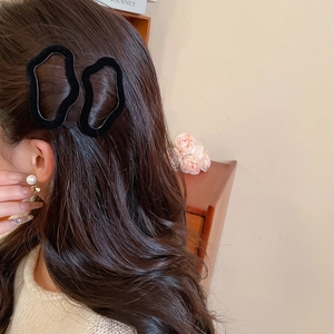 Close-up of black flocked irregular geometric hair clips worn on a woman's side profile