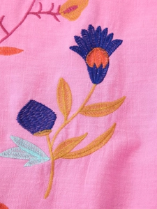 Macro detail of colorful floral embroidery on high-quality pink cotton linen cardigan