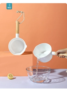 Détail d'une louche de cuisine blanche avec manche en bois et cordelette de suspension
