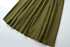 Vista dettagliata dell'orlo del vestito lungo verde oliva con pieghe eleganti e drappo